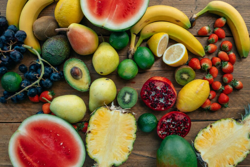 A colorful assortment of fresh fruits including bananas, strawberries, and watermelon arranged on a wooden table.